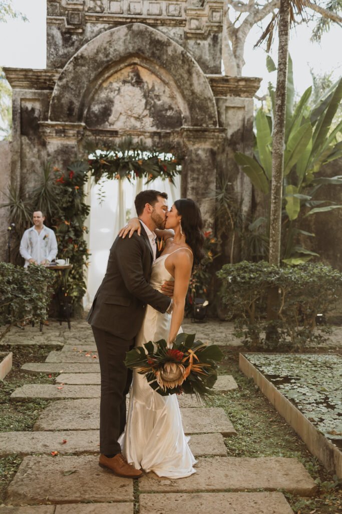 The newlyweds kissing on a stone path through the garden