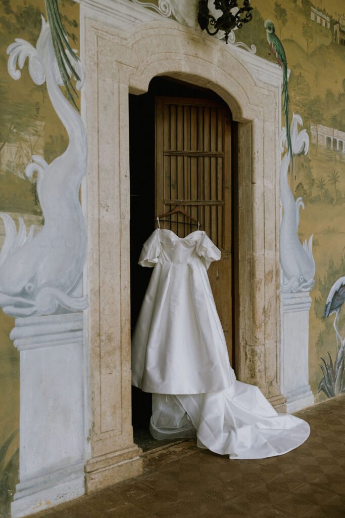 The dress hanging in the doorway of a painted hacienda room
