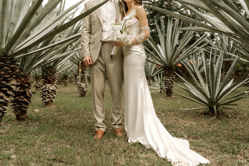 The couple standing among the agaves on the hacienda grounds