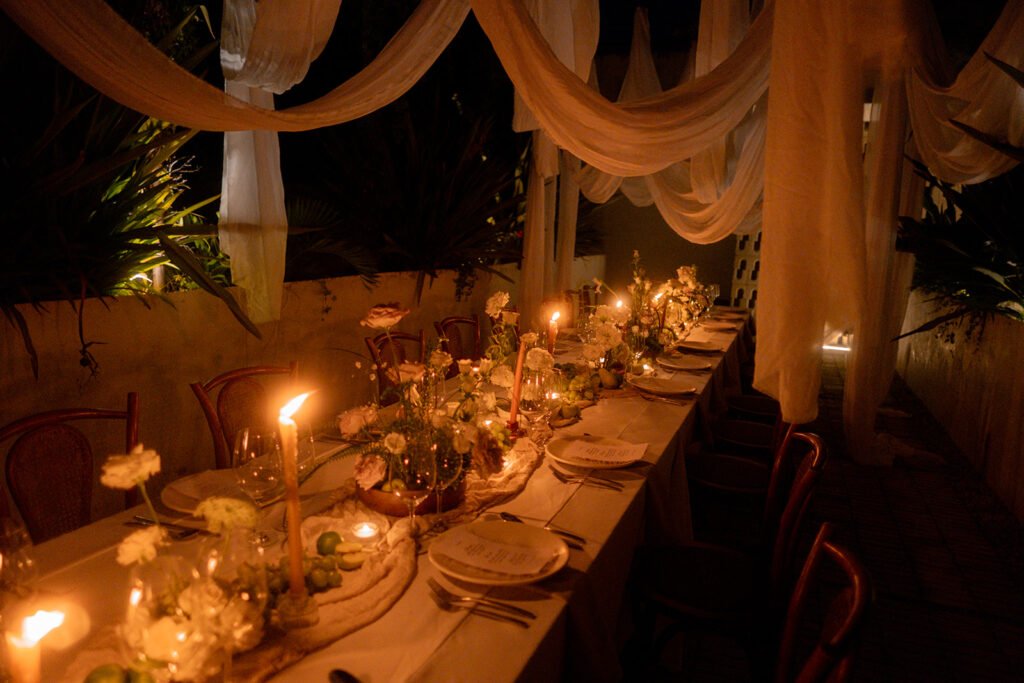The long table at night beneath draped linen and candlelight