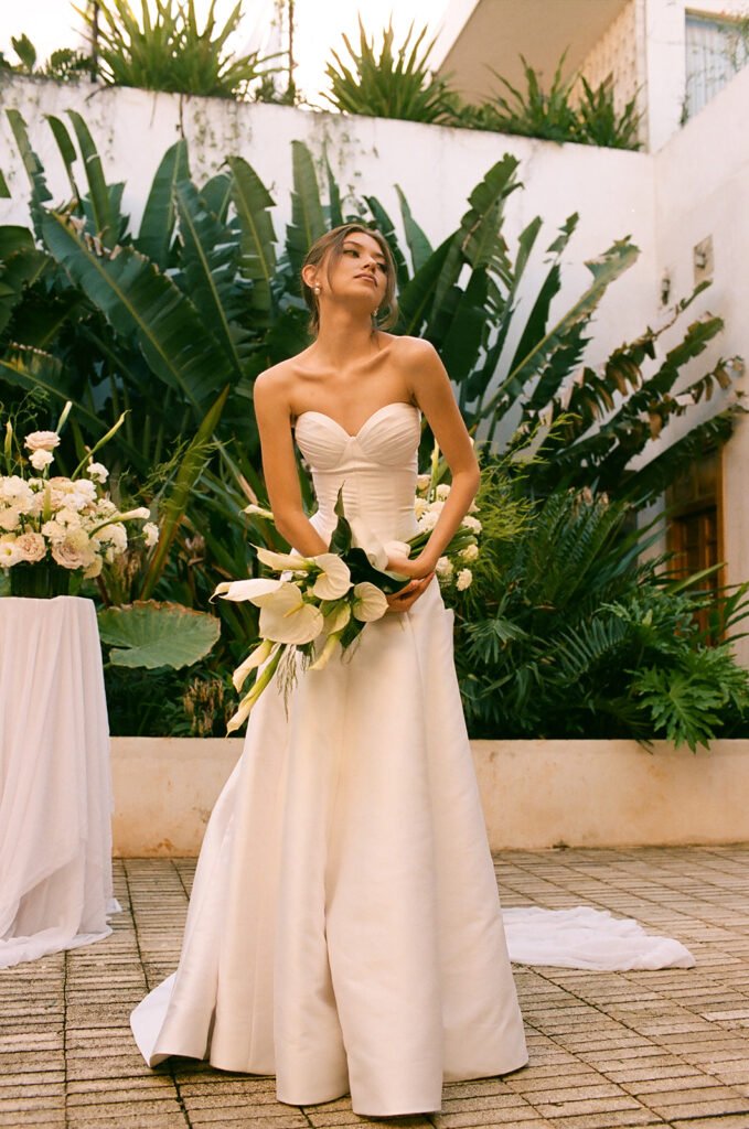 A bridal portrait holding a bouquet of calla lilies and anthurium against the banana palms