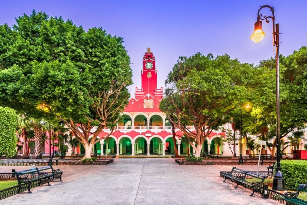 Plaza Grande in Mérida at dusk, the pink municipal palace and its clock tower framed by trees