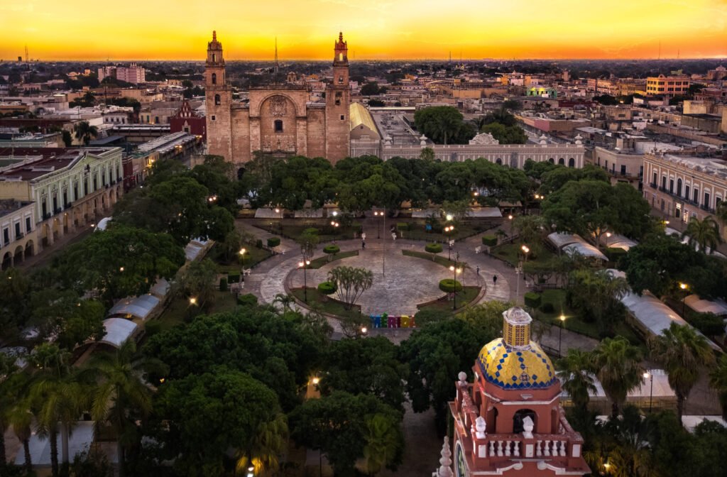 Plaza Grande and Mérida cathedral from the air at dusk, the square lit and full of trees